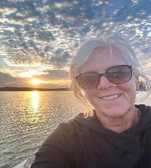 Linda Briggs smiling by the water at sunset